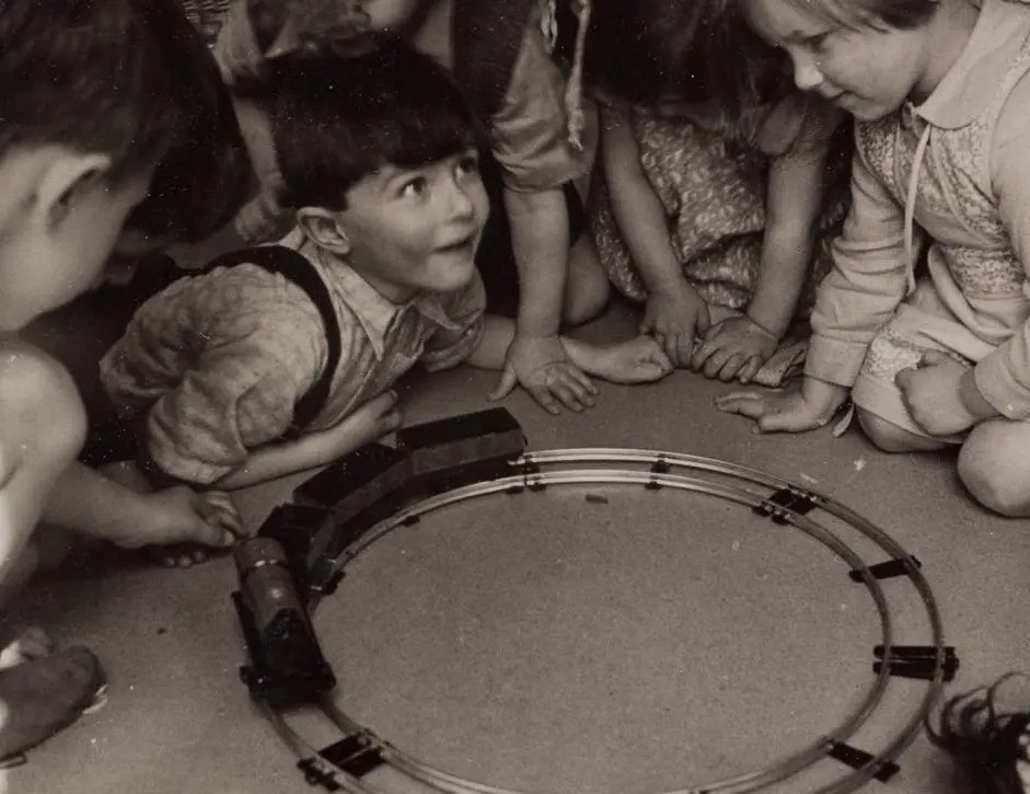 Children surrounding a train set in a playroom